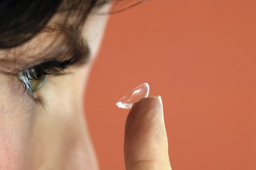 Woman holding contact lens to eye