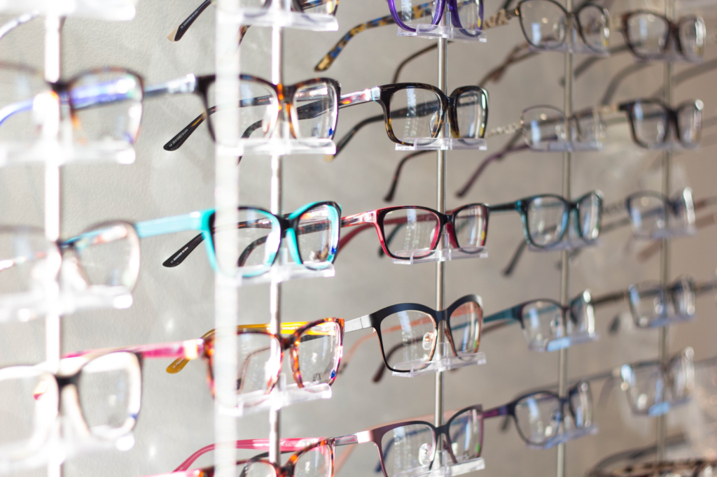 several rows of prescription eyeglasses on bright plastic display at an eye doctors office