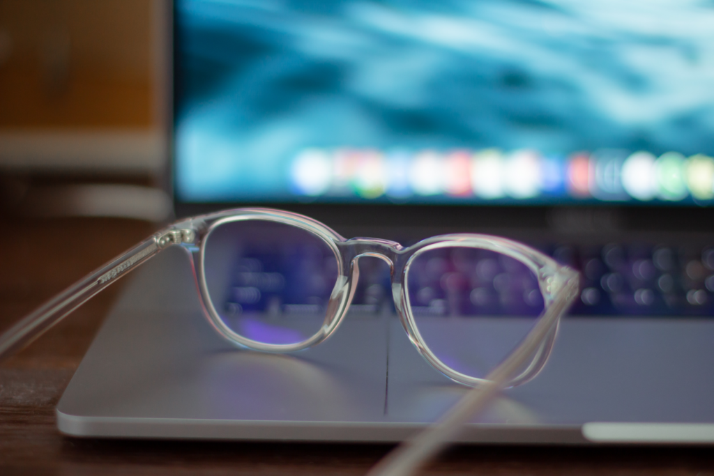 a clear plastic pair of eyeglasses with blue light coating sitting on an open laptop